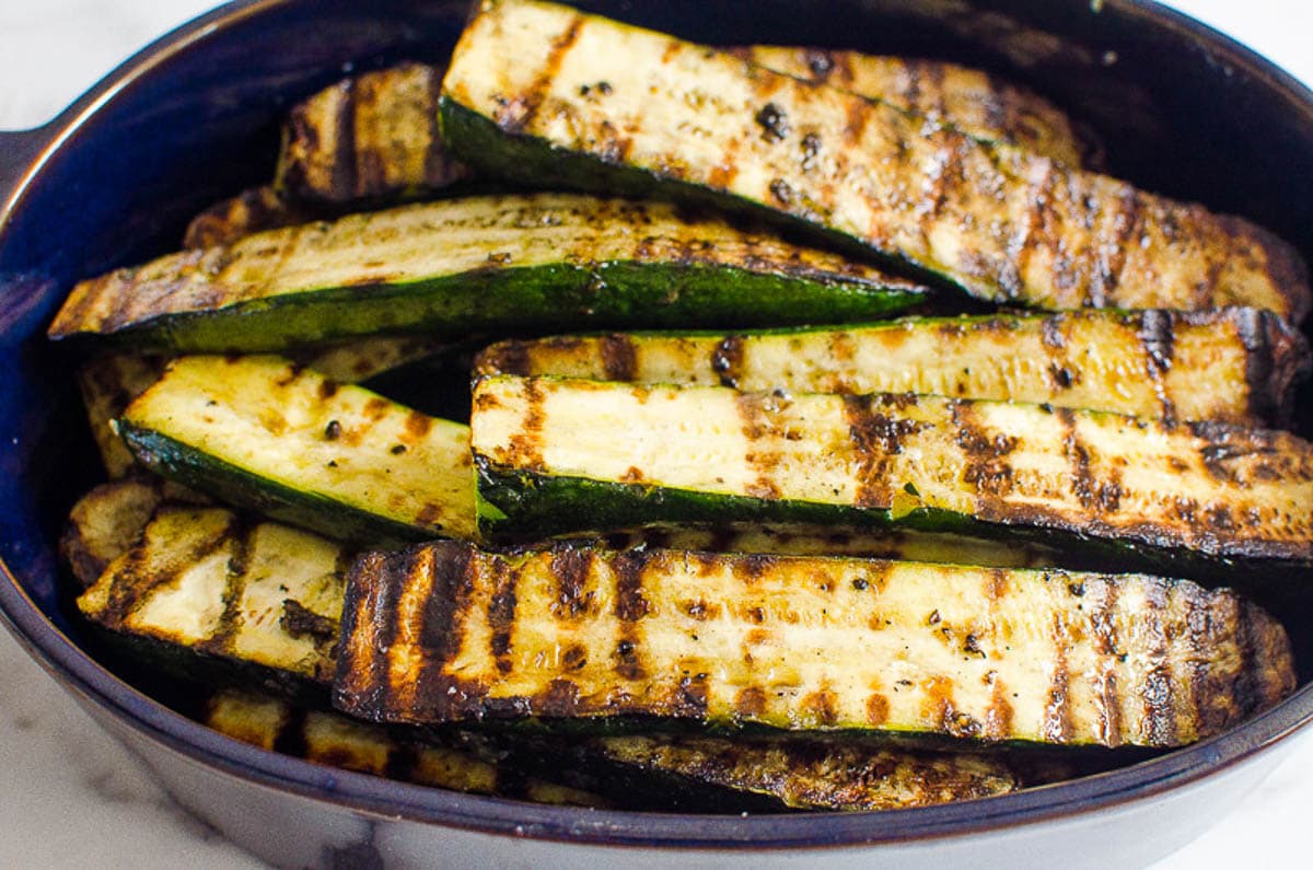Grilled zucchini halves in blue dish.