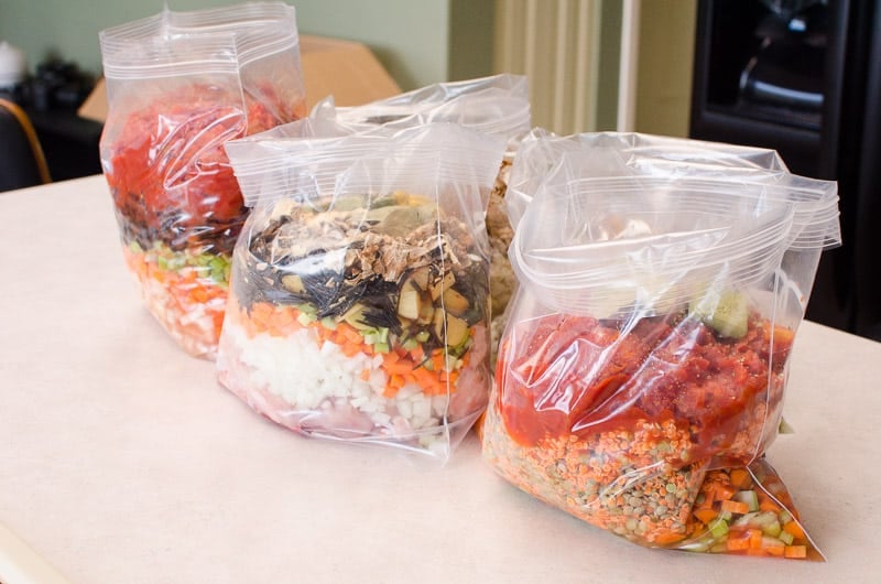 Three bags with freezer meals on a counter.