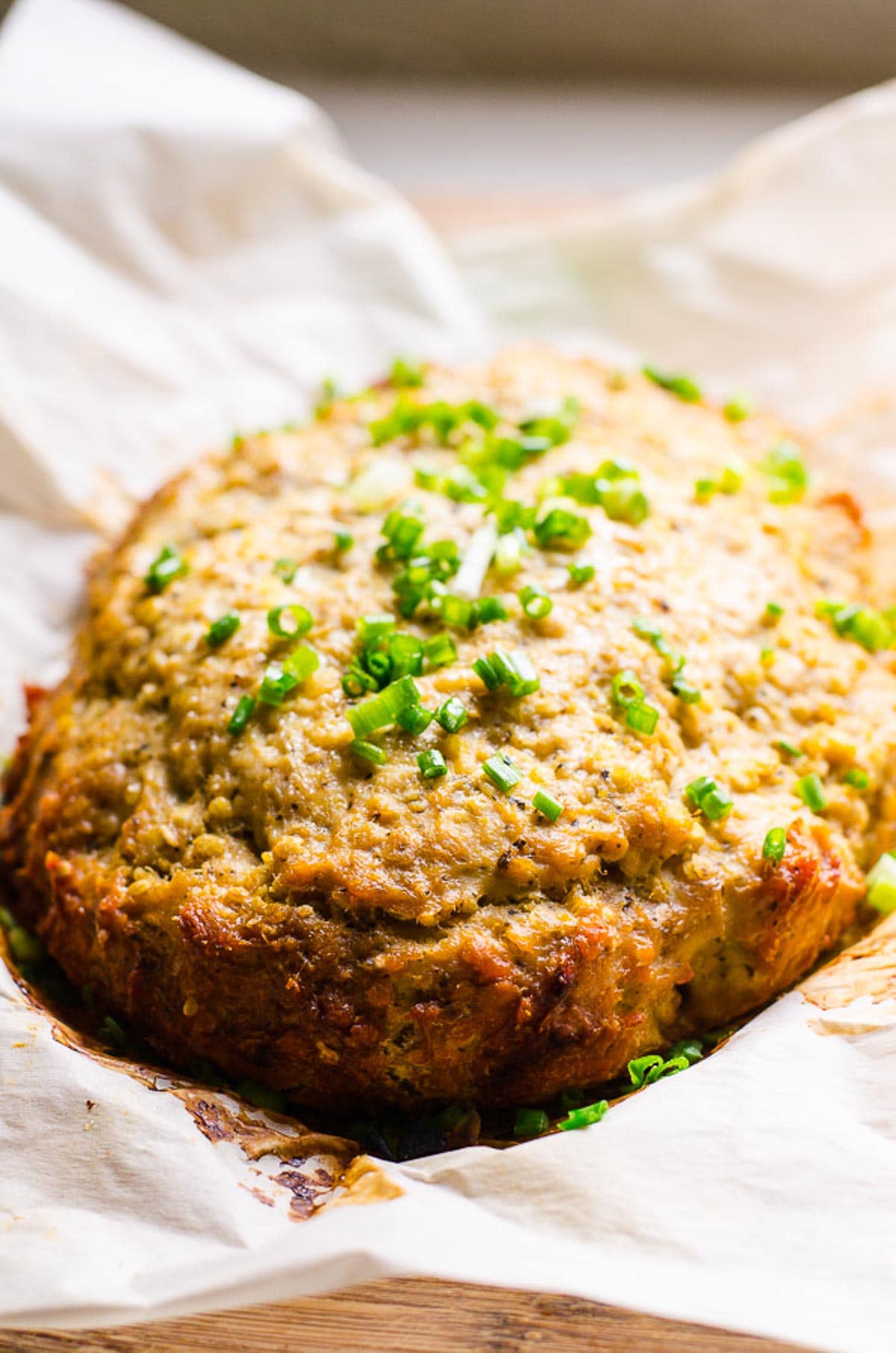 Cooked crockpot turkey meatloaf on parchment paper garnished with green onion.