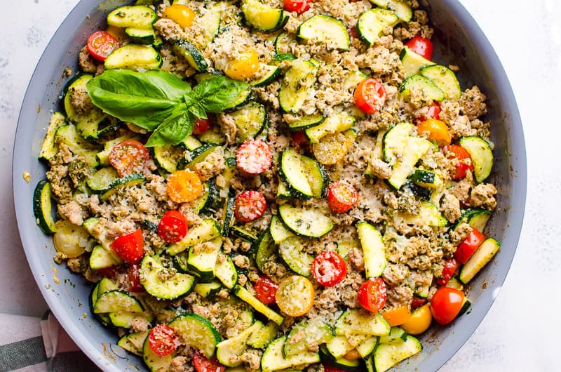 Ground turkey zucchini skillet with pesto, parmesan cheese and fresh basil in a skillet.